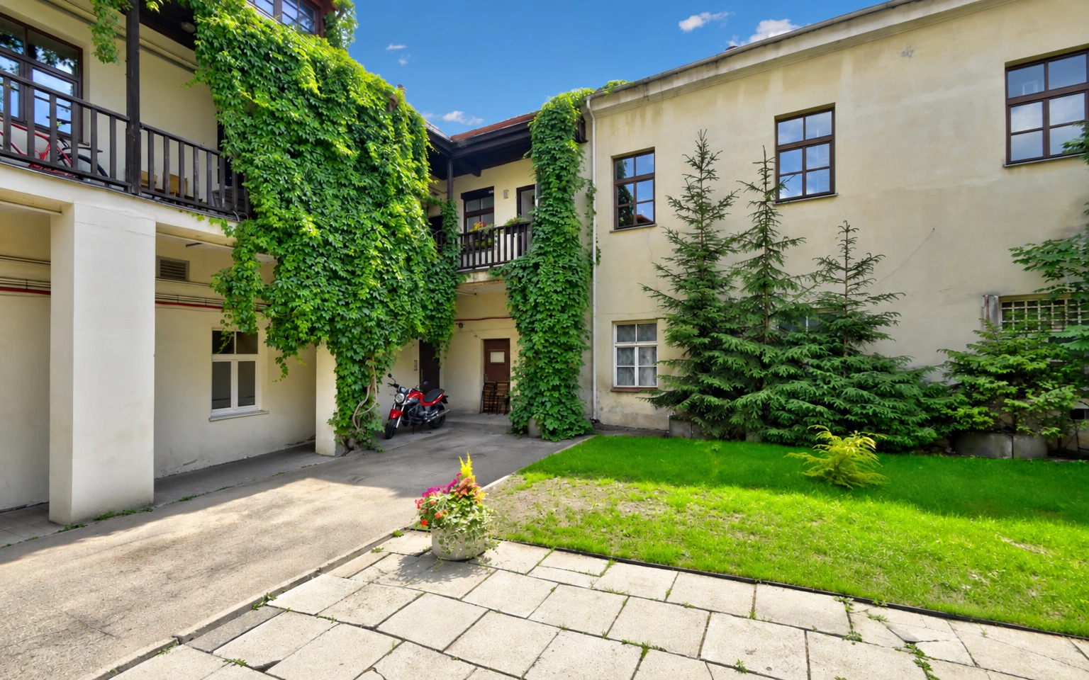 Ein Innenhof mit Rasen und mit Kletterpflanzen bewachsenen Gebäudewänden.