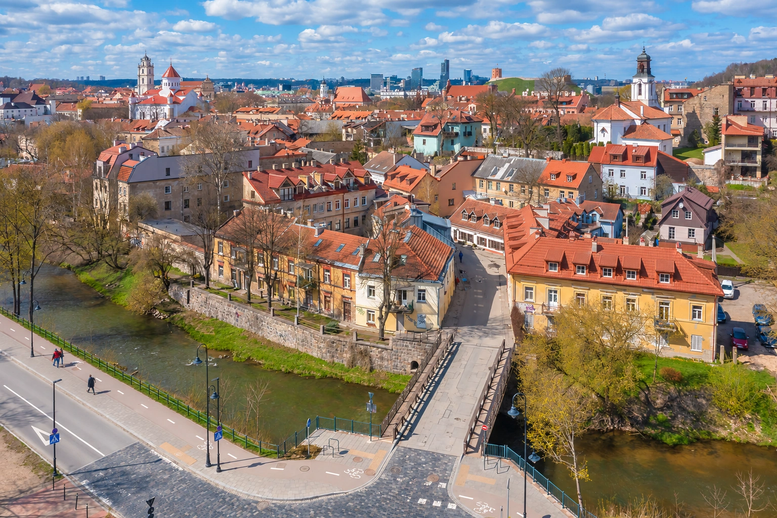 Senamiesčio panorama su raudonais pastatų stogais ir tiltu per upę.