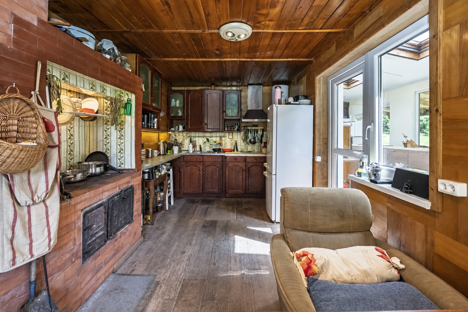 Kitchen with dark cabinets and a white refrigerator by the window.