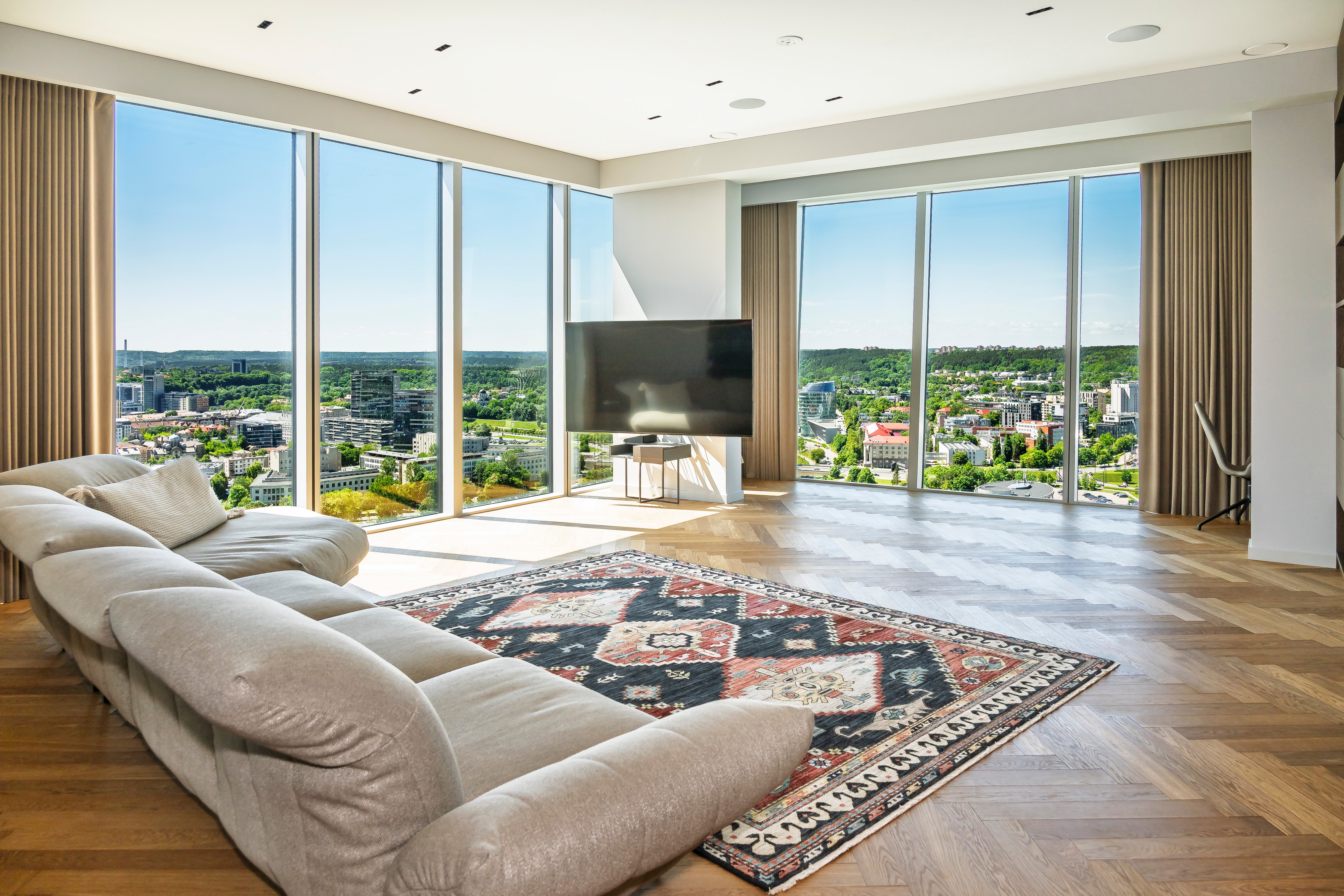 Living room with a corner sofa and large windows through which the city panorama can be seen.