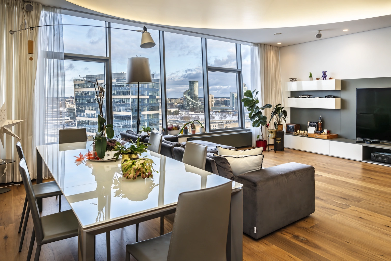 Living and dining area with large windows and a grey sofa.