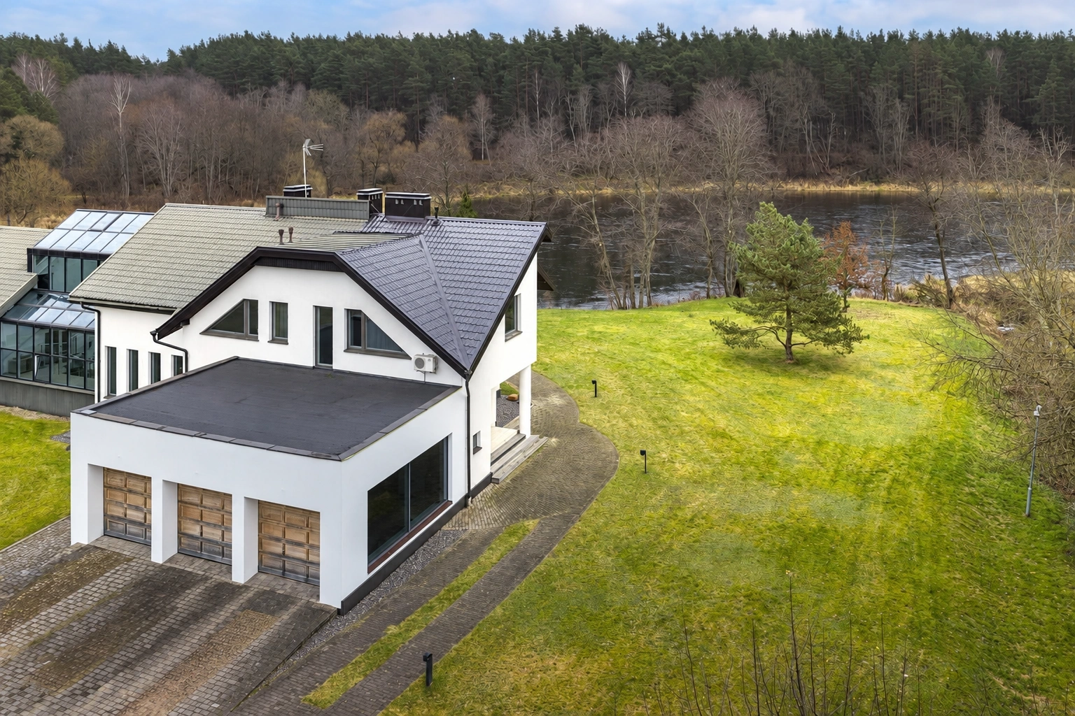 Ein weißes zweistöckiges Haus mit einer Garage steht neben einer großen Rasenfläche.