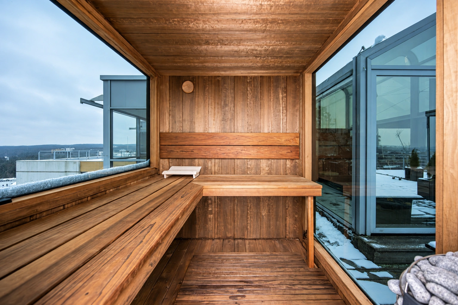 Eine Sauna mit Bänken entlang der Wände und großen Fenstern.