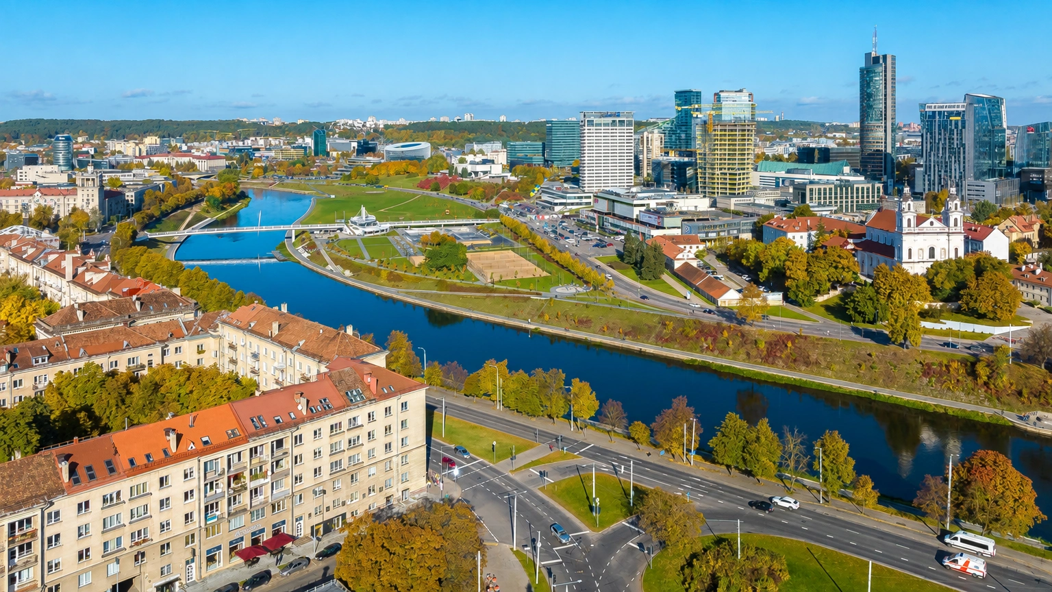 Miesto panorama su upe, tiltu ir aukštais pastatais tolumoje.