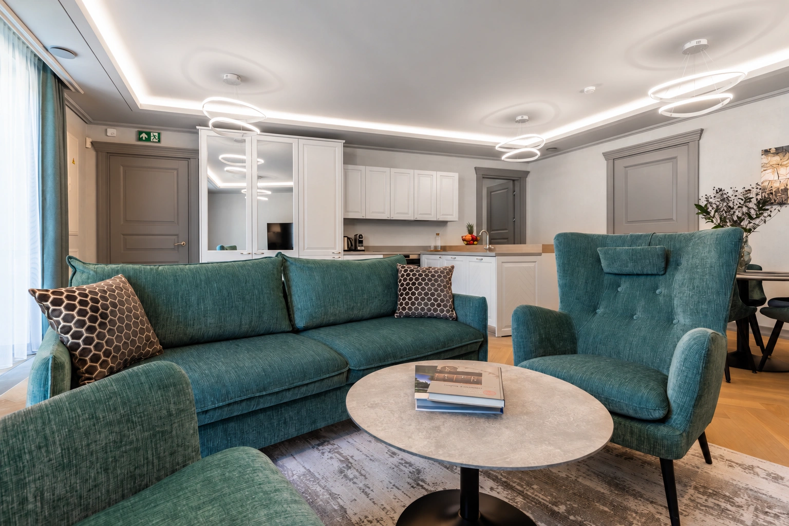 Svetainėje stovi žalsva sofa ir fotelis, o priešais juos – apvalus staliukas.