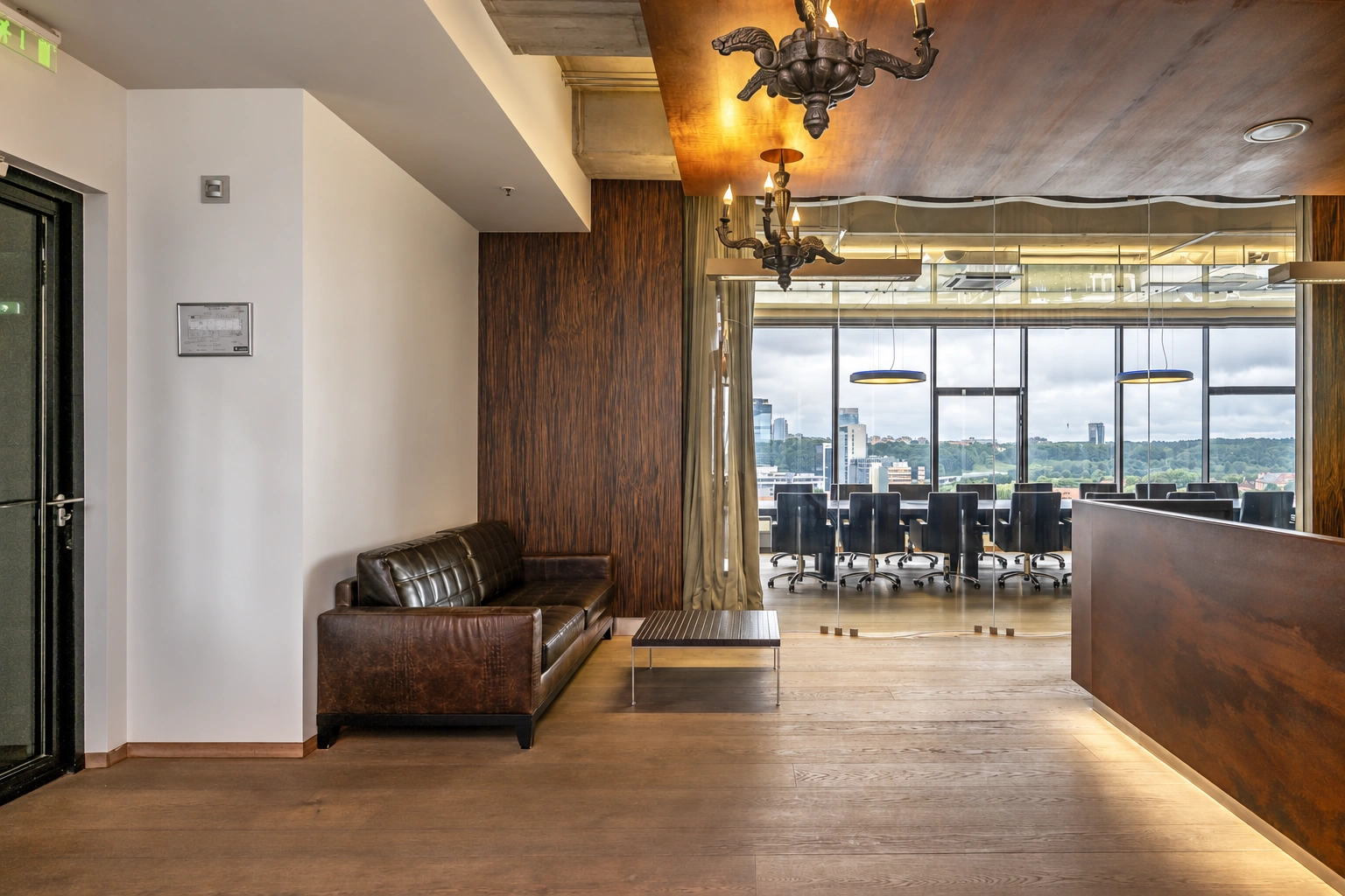 A room with a dark sofa by the wall and large windows.