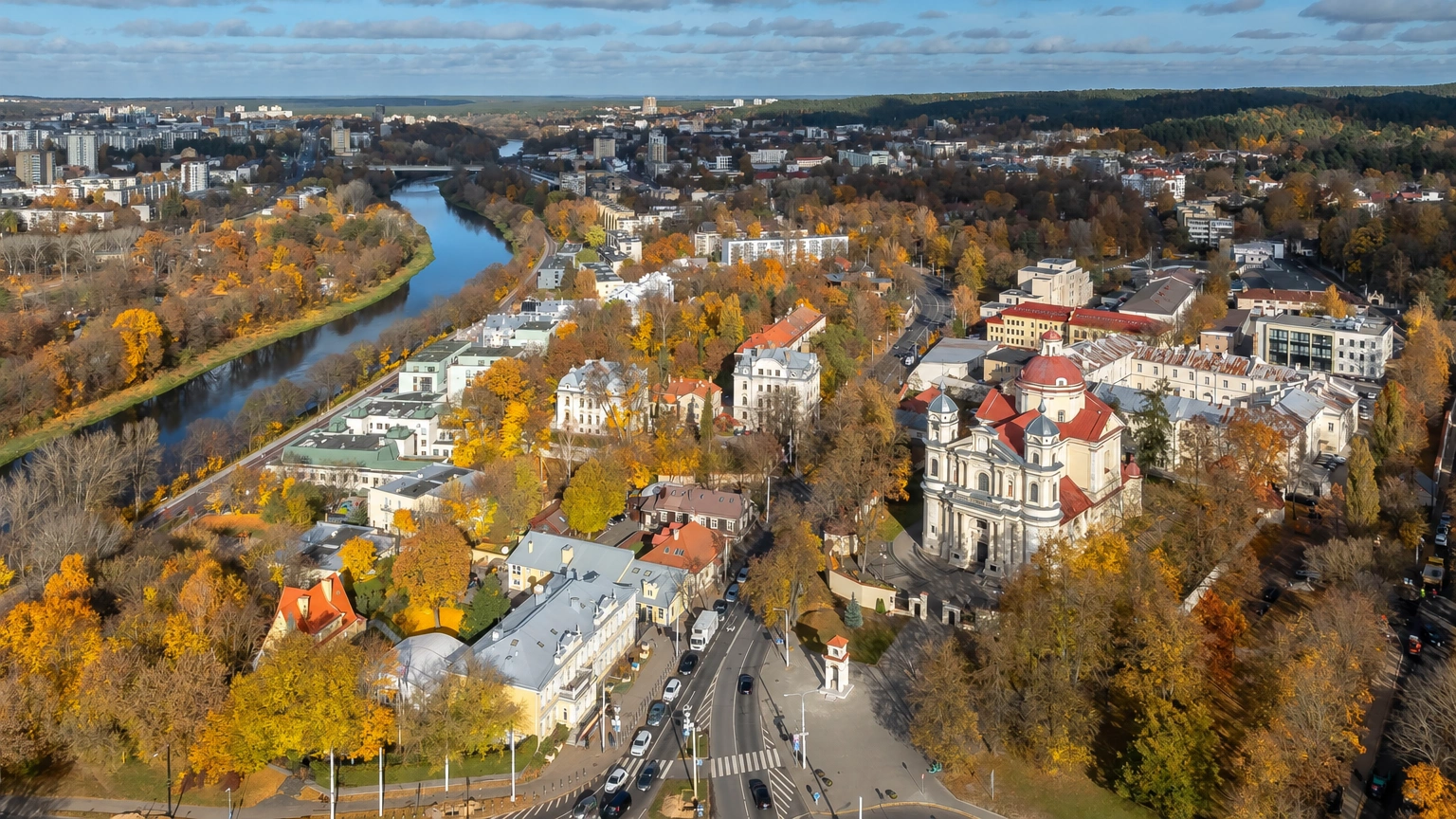 Stadtpanorama von oben mit einem sich schlängelnden Fluss und einer Kirche zwischen den Gebäuden.
