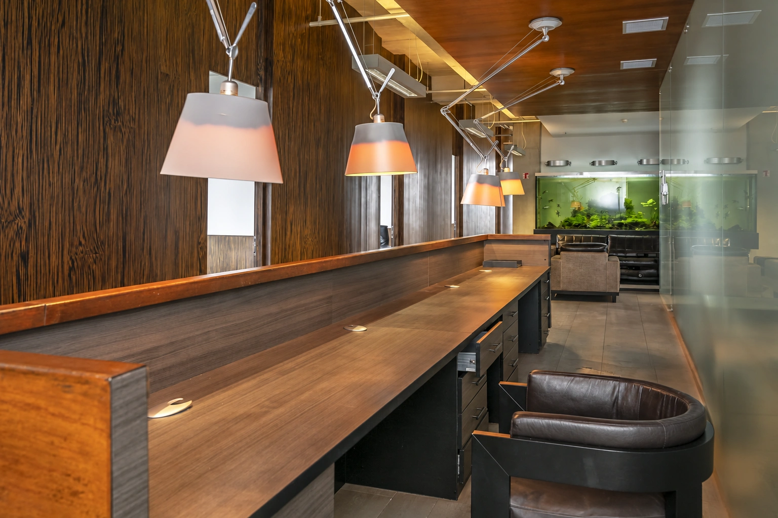 There are chairs at a long bar counter, and light fixtures hang above it.