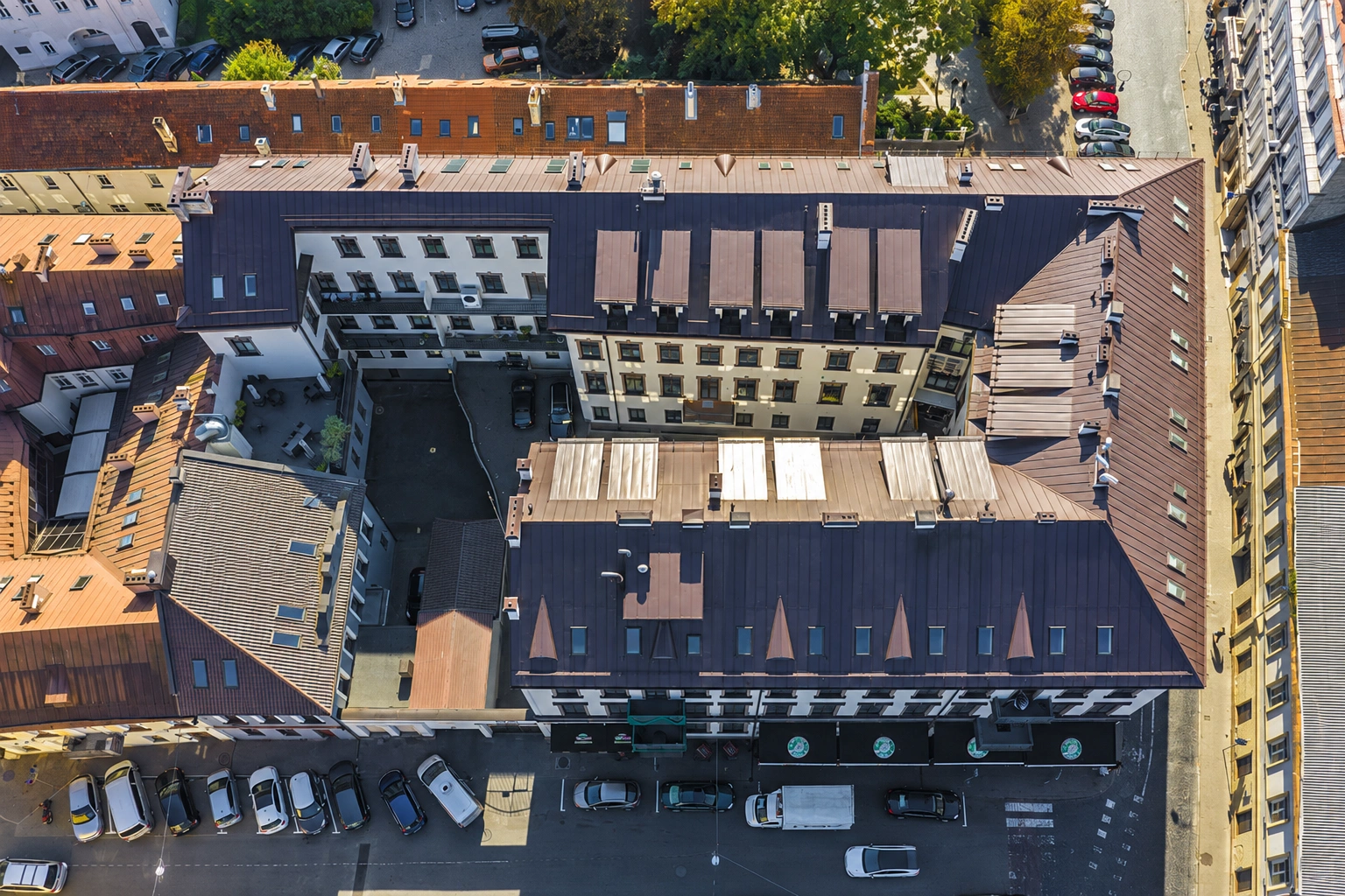 Buildings seen from above, with an inner courtyard and cars parked along the street.