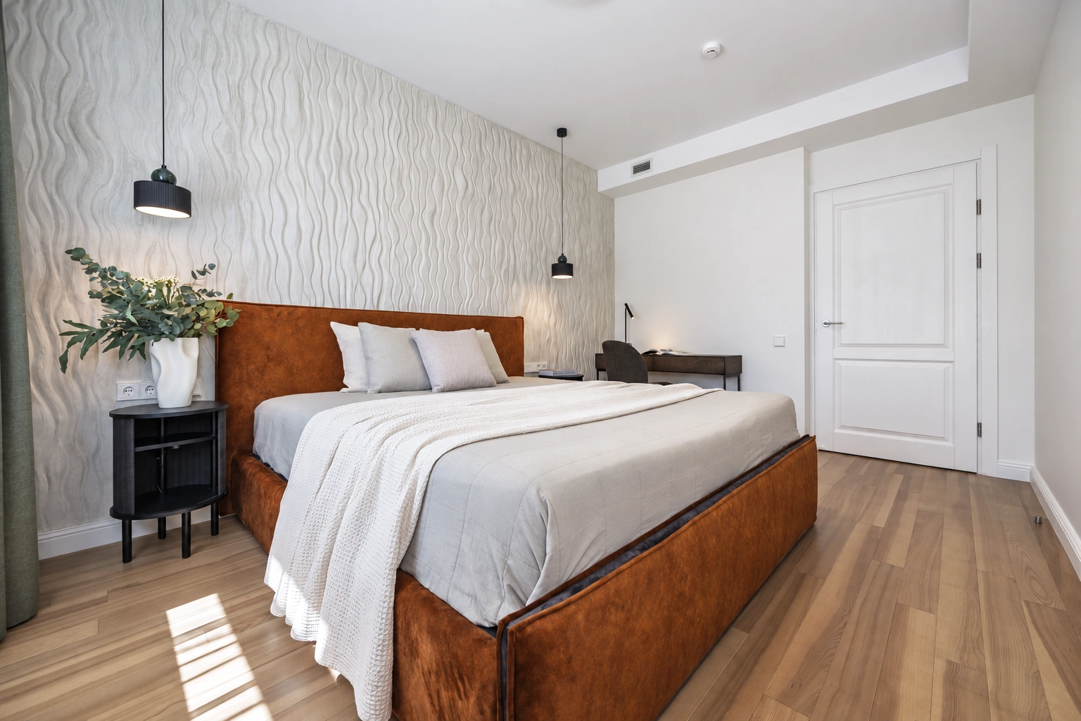 Schlafzimmer mit einem Doppelbett, Pendelleuchten und weißen Türen.