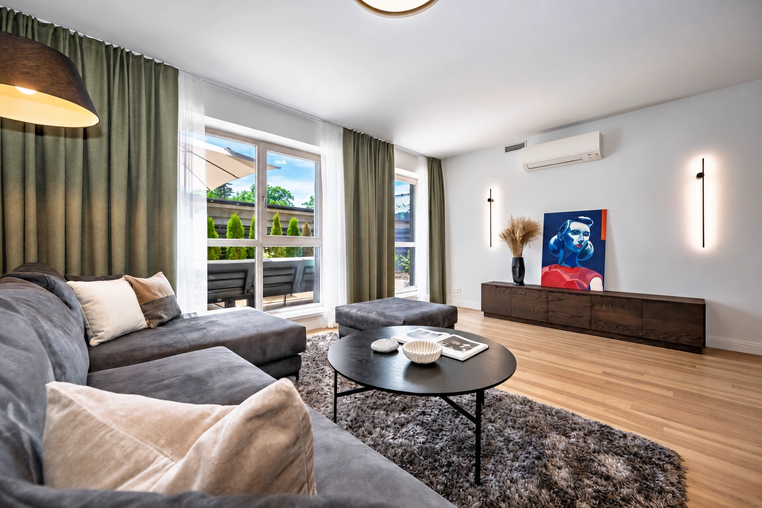 Im Wohnzimmer stehen ein graues Ecksofa und ein runder Couchtisch.