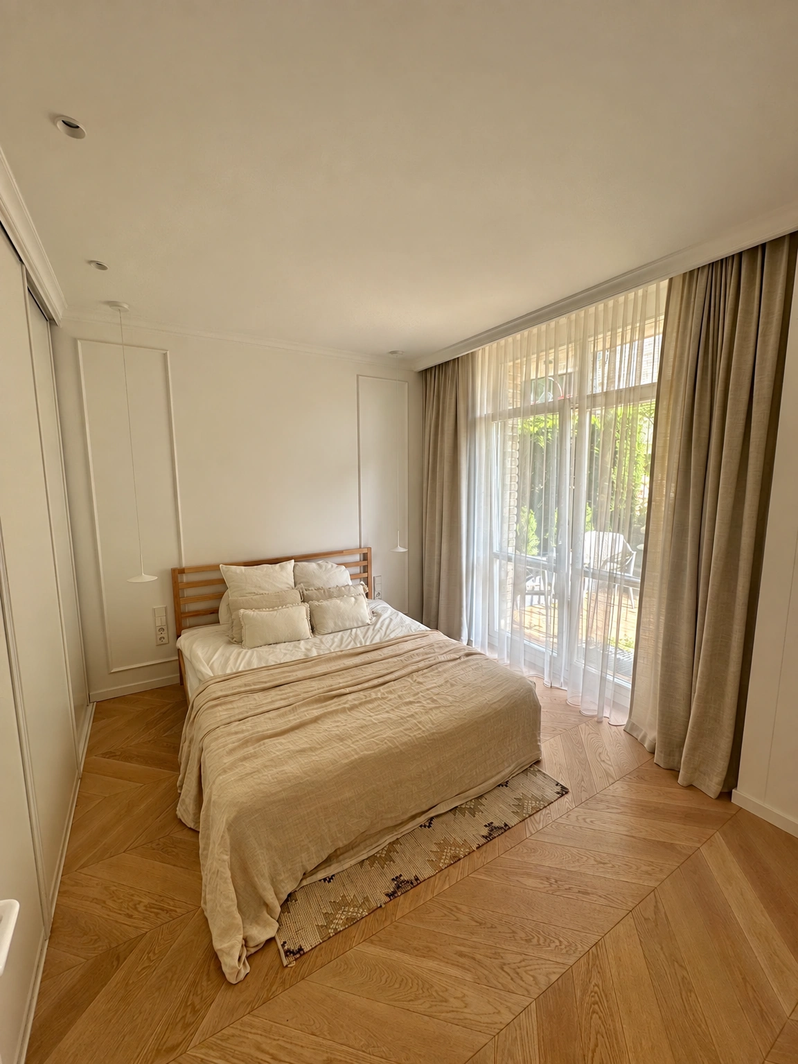 Ein Schlafzimmer mit einem Doppelbett und einem großen Fenster, das von Vorhängen bedeckt ist.