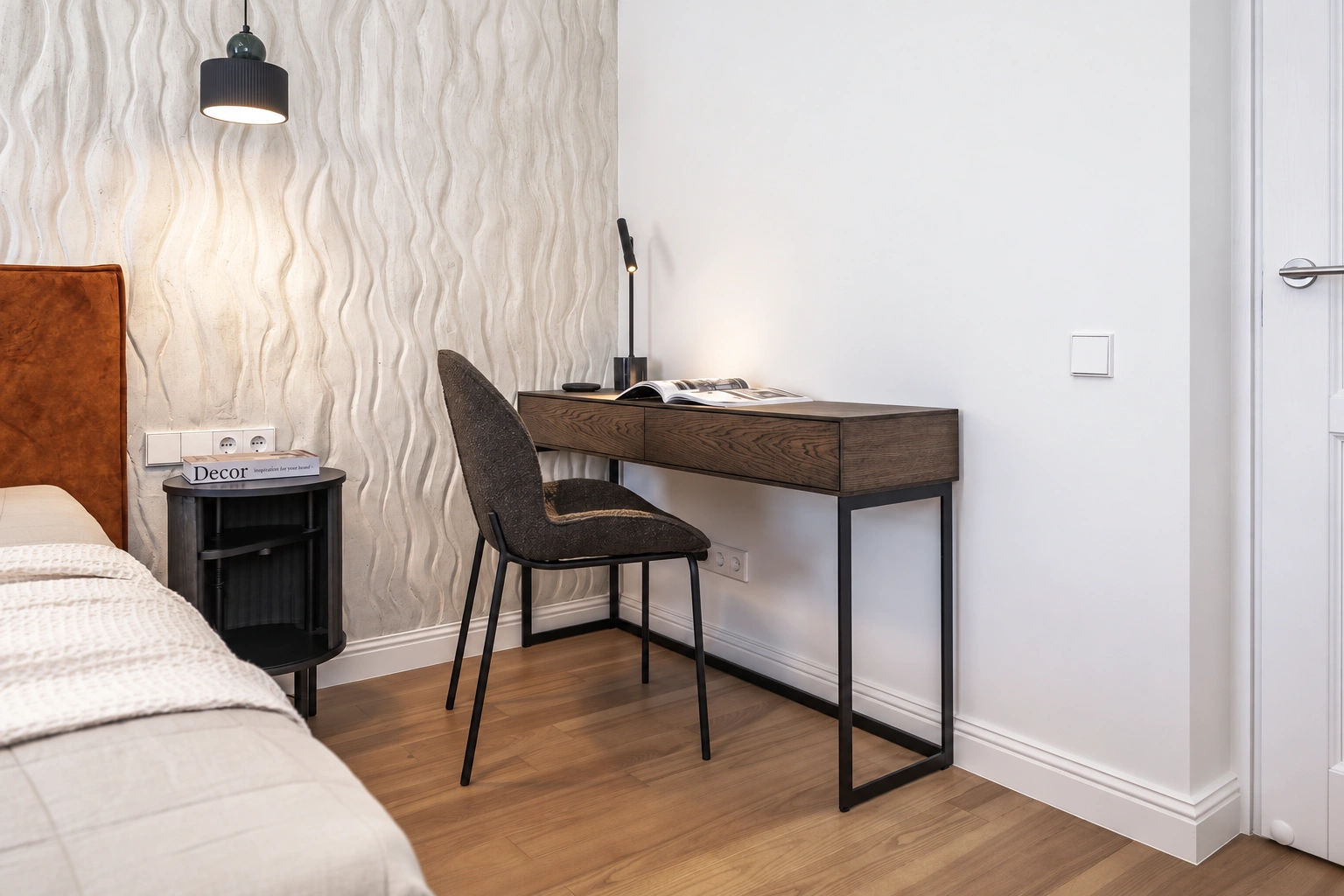 Eine Schlafzimmerecke mit einem Bett und einem Schreibtisch, an dem ein Stuhl steht.