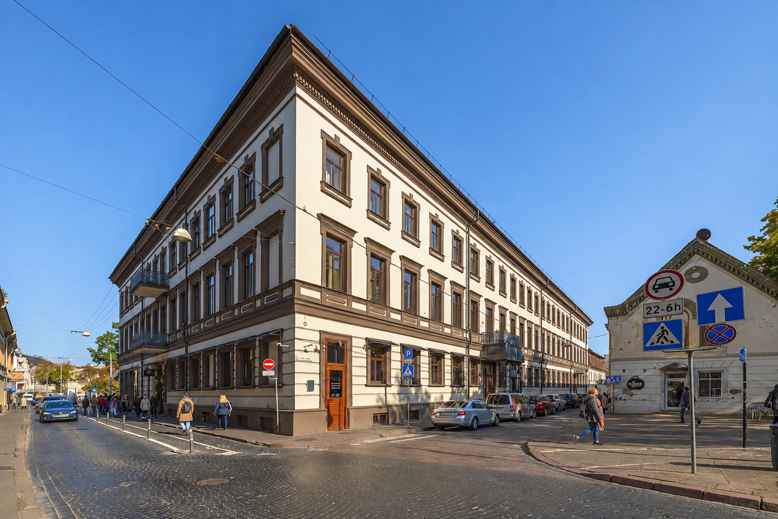 A multi-storey corner building with many windows stands near a street intersection.