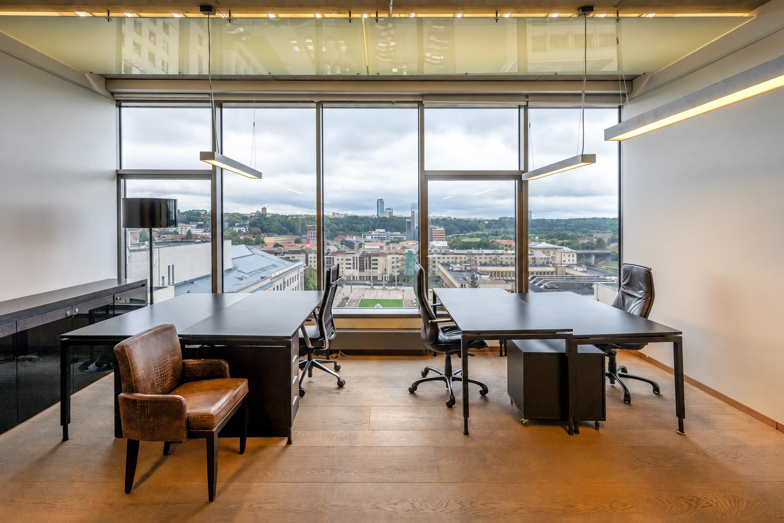 Office space with desks and large windows through which the city can be seen.