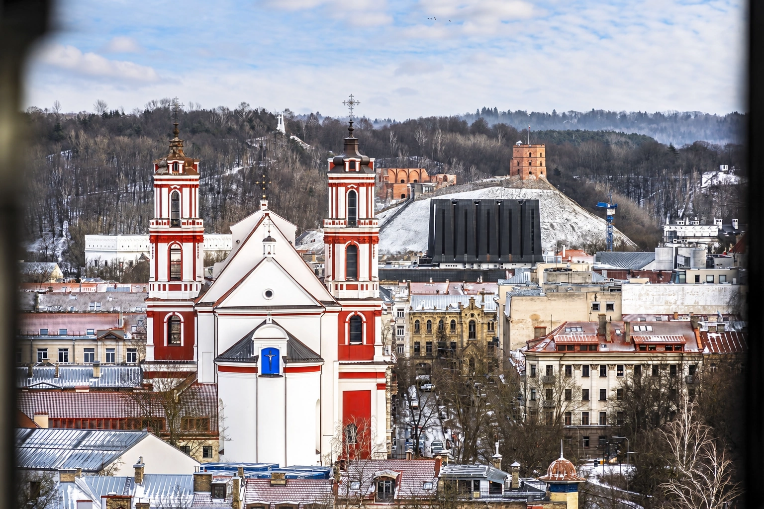 City panorama with a twin-towered church and snow-covered roofs of the surrounding buildings.