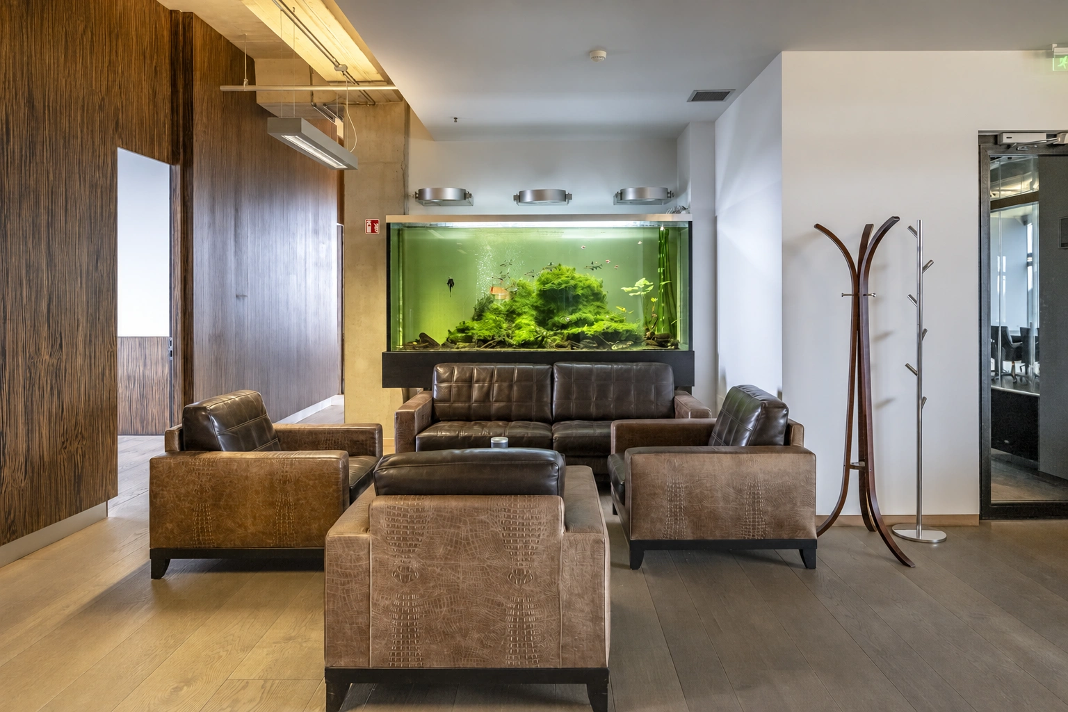 A sofa, armchairs, and a large aquarium with plants can be seen in the relaxation area.