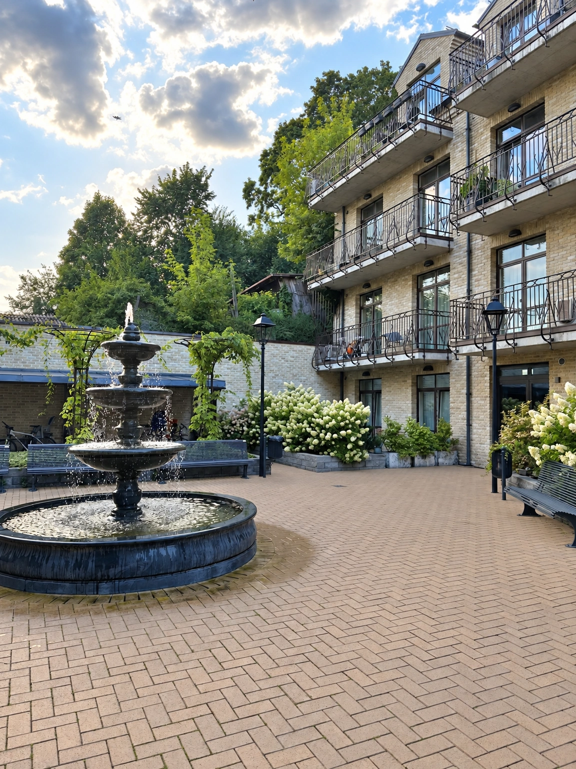 Im Innenhof sind ein Brunnen, Bänke und die Fassade eines Gebäudes mit Balkonen zu sehen.