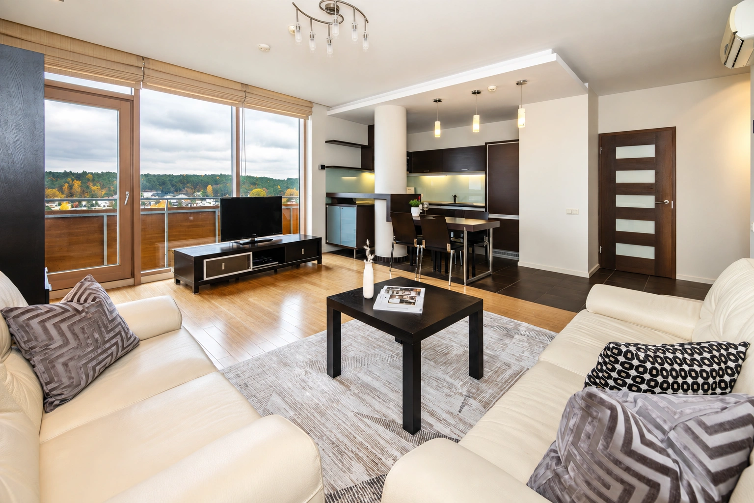 Wohnzimmer mit zwei hellen Sofas und großen Fenstern.