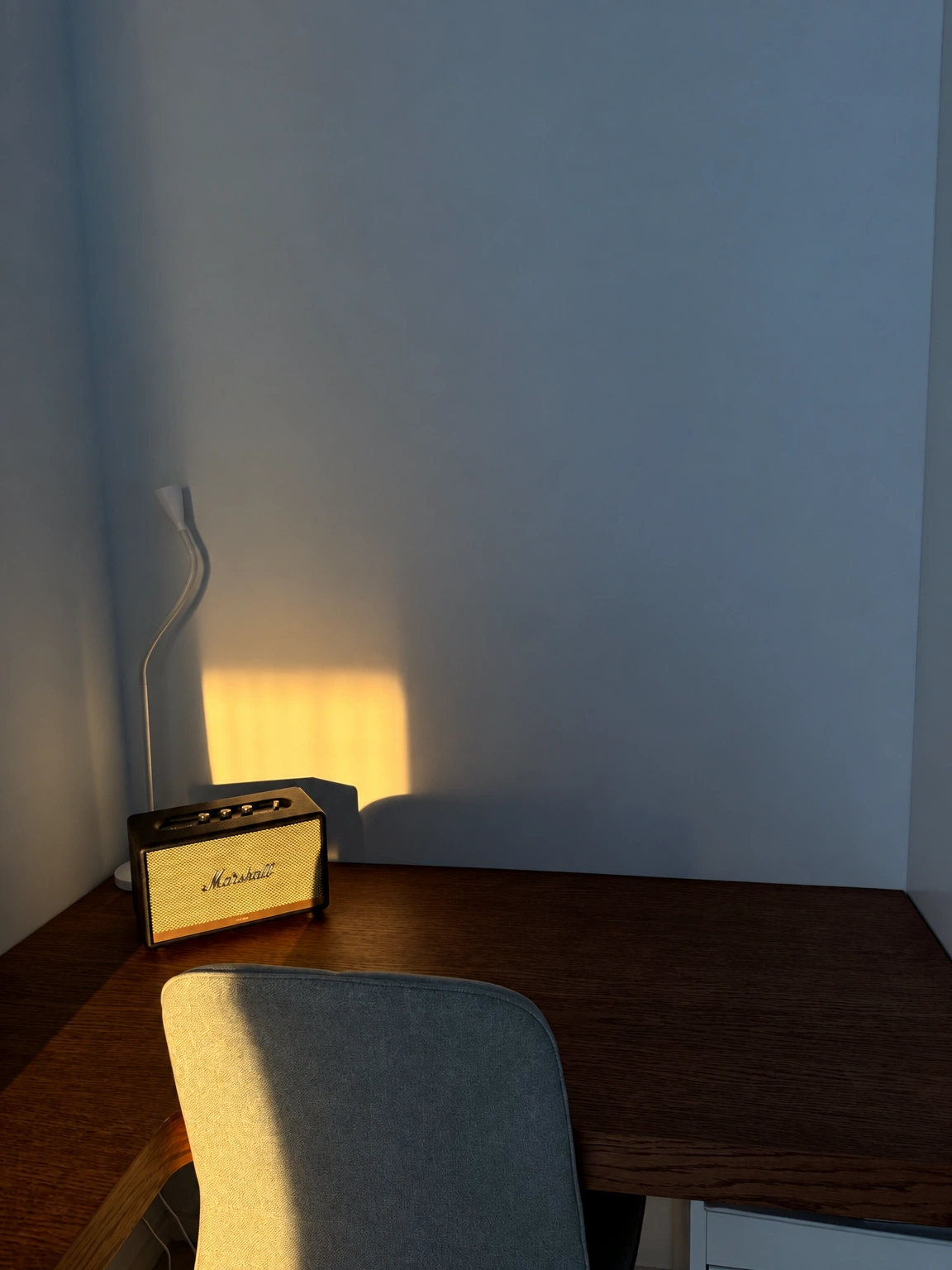 A gray chair stands beside a dark table, and a small speaker has been placed on the tabletop.