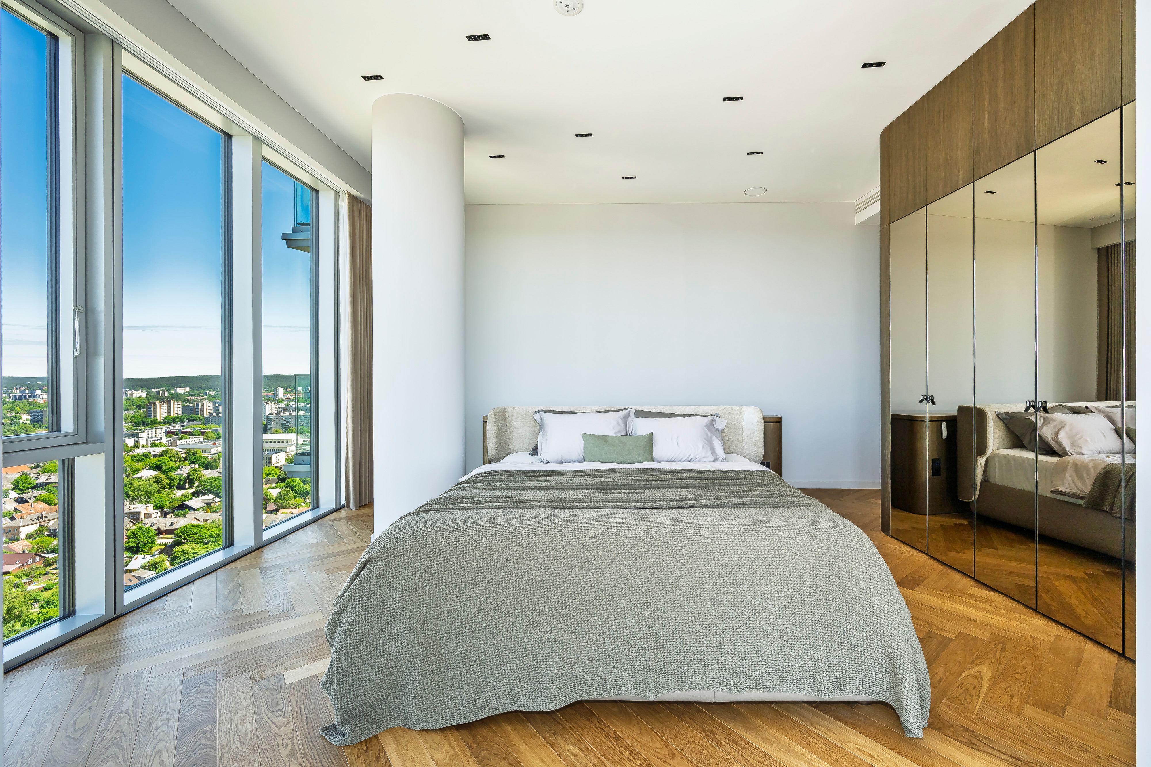 Bedroom with a double bed, large floor-to-ceiling windows and mirrored wardrobe doors.