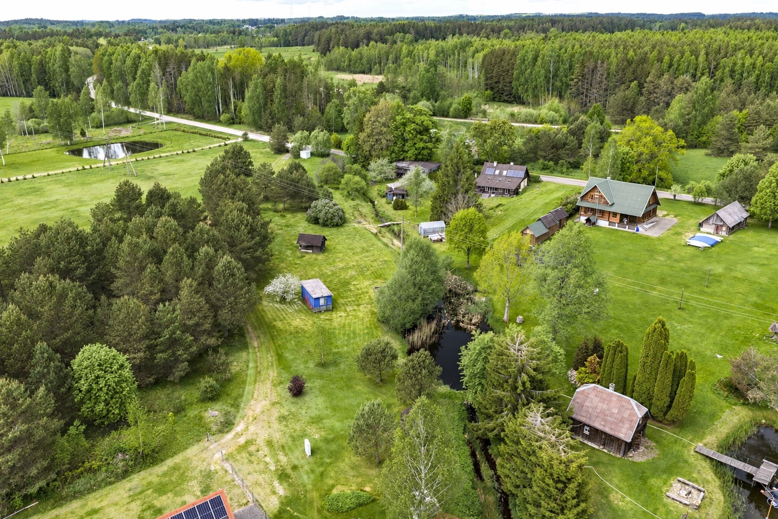 Several buildings surrounded by meadows and trees are visible from above.