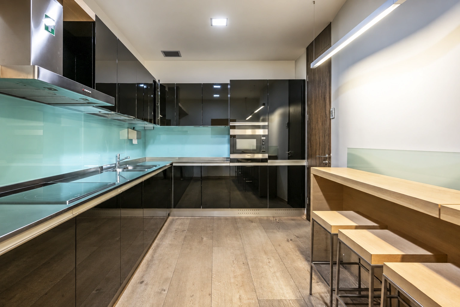 A kitchen with dark cabinets and a bar set along the wall, with stools.