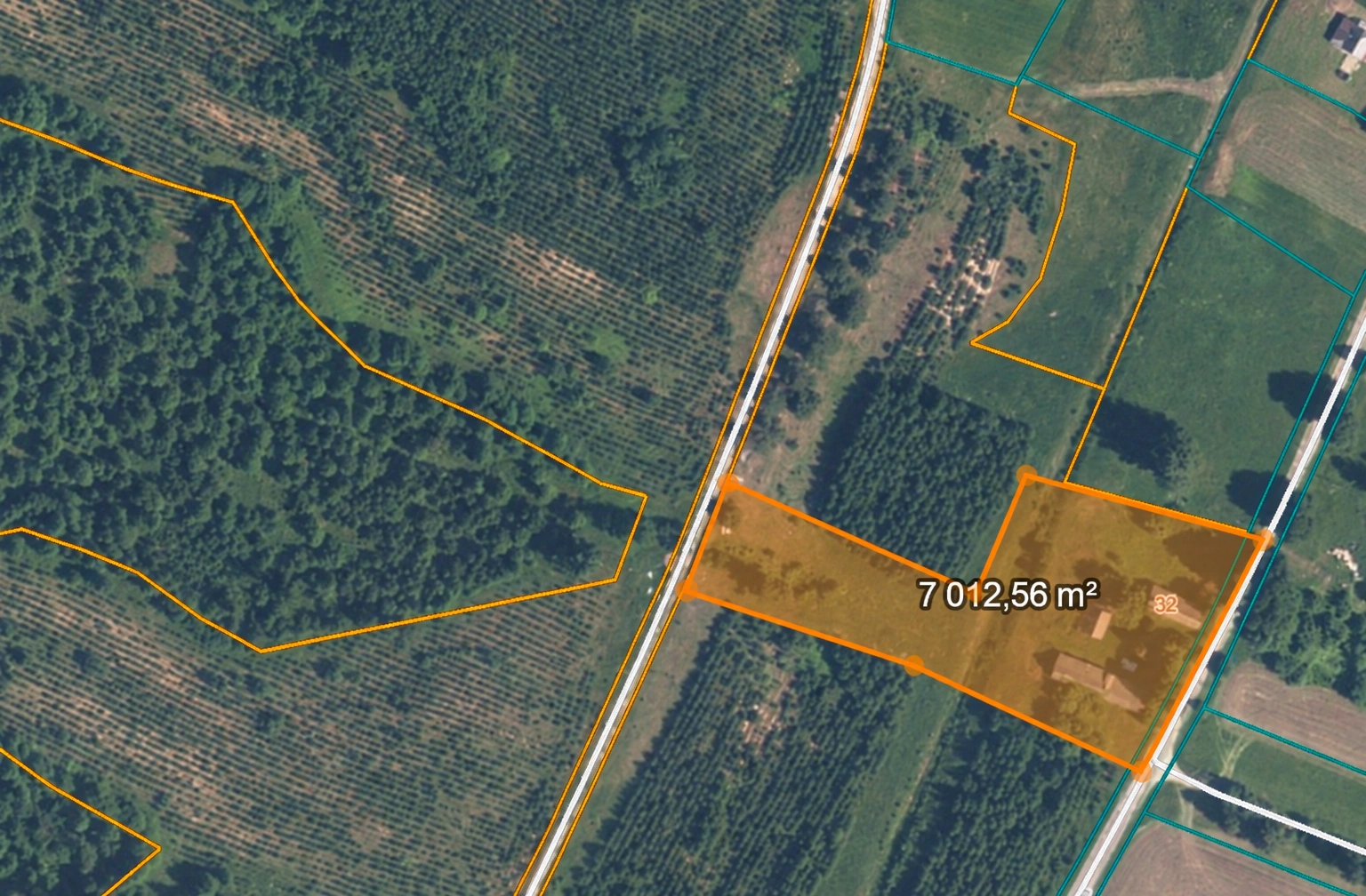 Die Ansicht von oben zeigt ein orange markiertes Grundstück neben einer Straße und einem Wald.