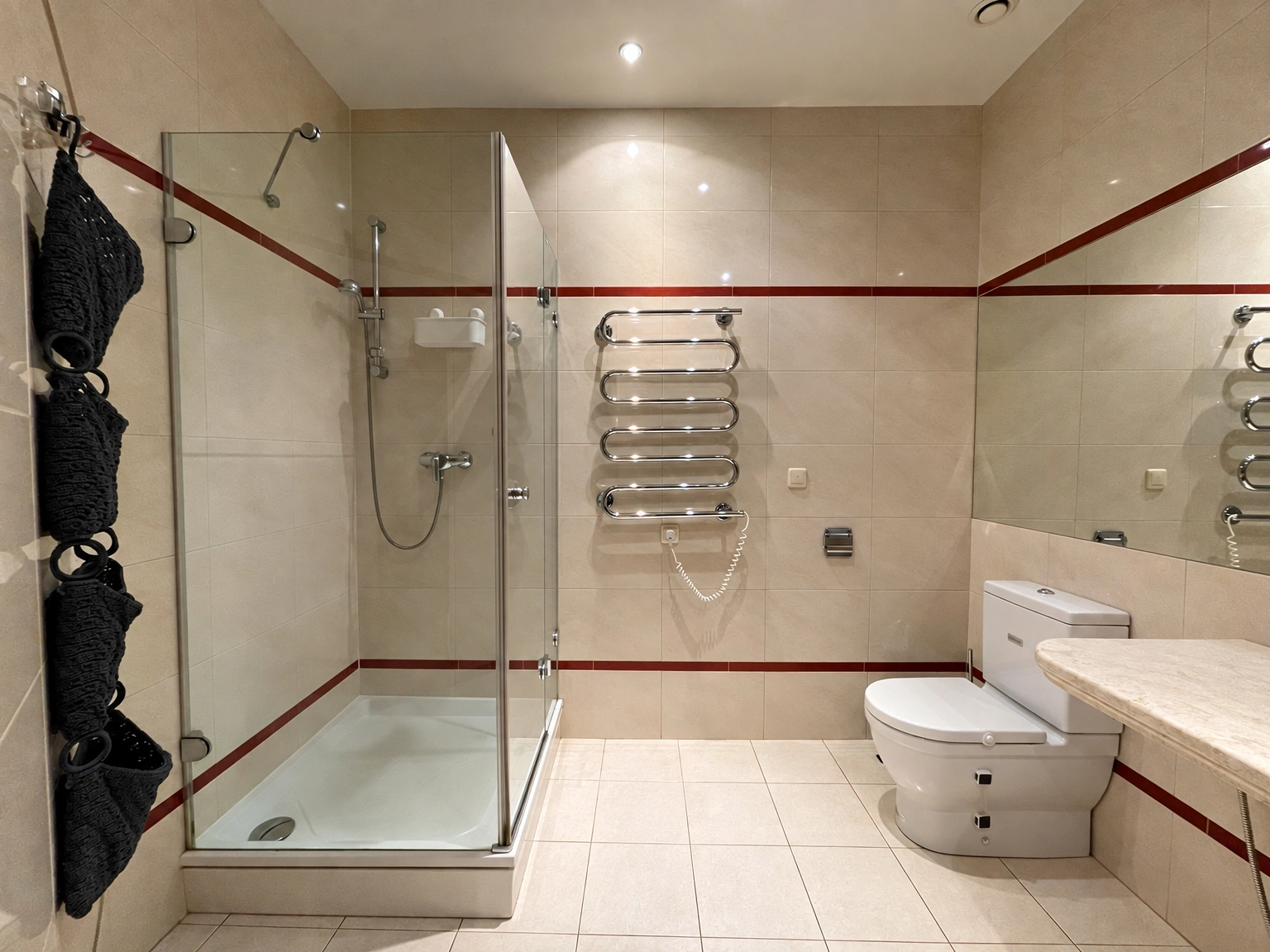 Badezimmer mit einer Duschkabine aus Glas und einem wandmontierten Handtuchtrockner.